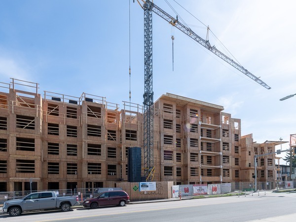 Image of wood frame budiling being constructed by crane